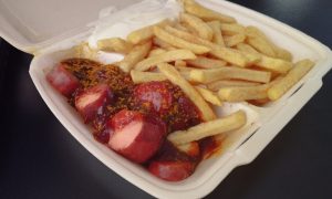 Frische Currywurst mit Pommes und Mayonnaise in einer umweltfreundlichen Verpackung von „Pommes Goldgelb“ in Verden.