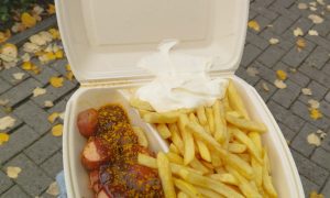 Frische Currywurst mit Pommes und Mayonnaise in einer umweltfreundlichen Verpackung von „Pommes Goldgelb“ in Verden.