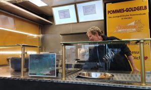 Mitarbeiter der evangelischen Pommesbude „Pommes Goldgelb“ in Verden bereitet Pommes hinter der Theke zu.